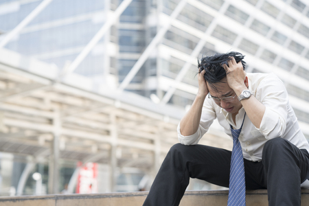 Young depressed businessman sitting on the stairsの写真素材