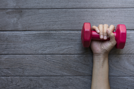 woman hand holding red dumbbell on wood tale backgroundの写真素材
