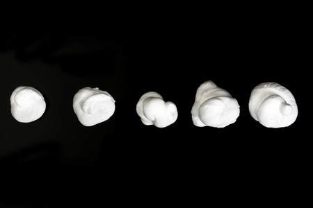Collection of various strokes of shaving cream on black background
