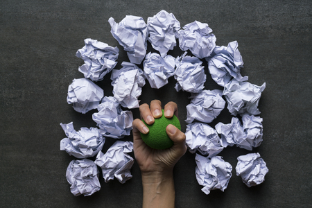 woman hand holding stress ball with crumpled paper backgroundの写真素材
