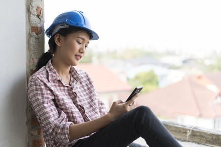 The asian woman engineer who use mobile phone in construction building at breaking timeの写真素材