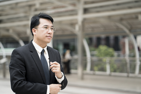 Young confident Asian businessman in suit standing city outdoor.の写真素材