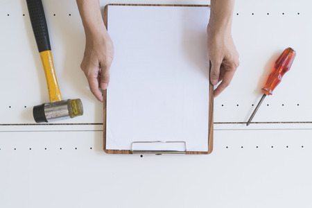 Craftsman with empty white clipboard in his hands, diy and repair home conceptの写真素材