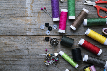 Sewing accessories and fabric on wooden table, top view