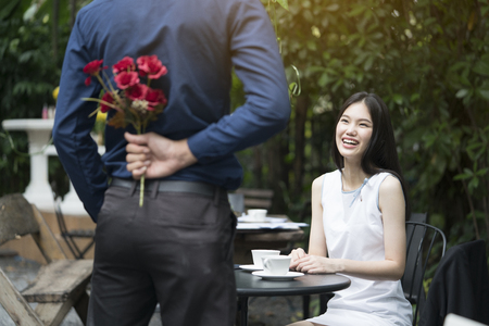 A man is proposing marriage to a smiling woman with a lovely flower bouquet in a beautiful garden, lover and couple concept, surprising proposalの写真素材