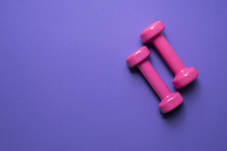 two pink dumbbell on purple background, sport and healthy conceptの写真素材