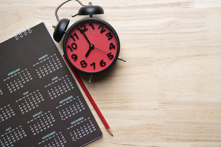 close up of calendar, alarm clock and pencil on the table, planning for business meeting or travel planning conceptの写真素材