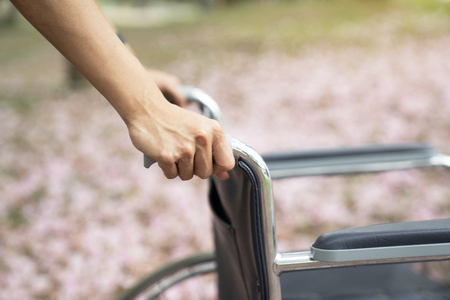 Empty wheelchair pushed by nurse's handsの写真素材