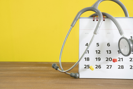 stethoscope and calendar on the table with yellow background, schedule to check up healthy conceptの写真素材