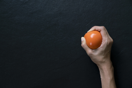 woman holding a stress ball in her hand on black backgroundの写真素材