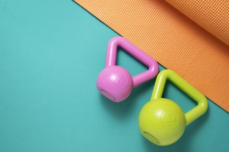 Kettlebell and yoga mat  on a green background, sport and healthy concept