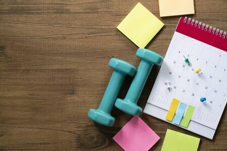 Top view of  and calendar and dumbbell on the wooden table background, schedule to check up healthy conceptの写真素材
