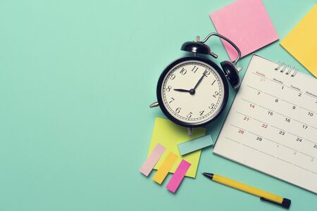 close up of calendar and alarm clock on the green table background, planning for business meeting or...