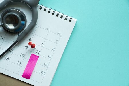 Top view of stethoscope and calendar on the green background, schedule to check up healthy concept