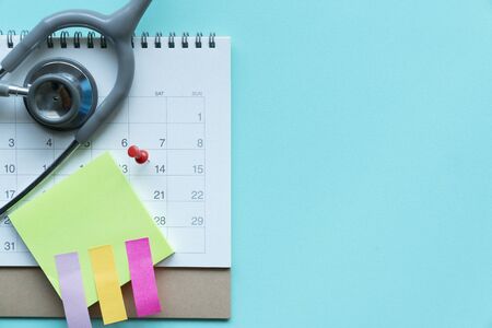 Top view of stethoscope and calendar on the green background, schedule to check up healthy conceptの写真素材