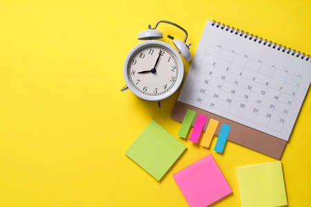 close up of calendar and alarm clock on the yellow table background, planning for business meeting or travel planning conceptの写真素材