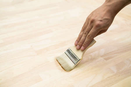 Applying protective varnish by brush on a wooden furnitureの写真素材