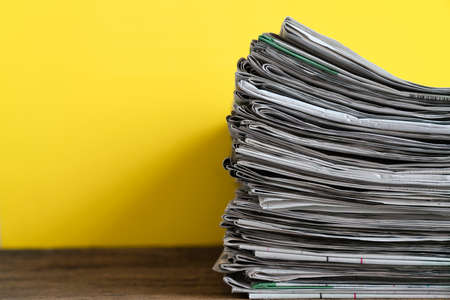 close up newspapers folded and stacked on yellow background on the tableの写真素材