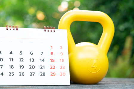 Time for exercising calendar and kettlebell sport equipment on the table background