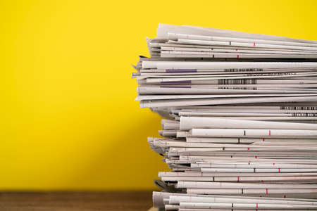 close up newspapers folded and stacked on yellow background on the tableの写真素材