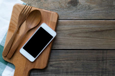 mobile phone served on wood plate on the wooden table, food order menu online delivery concept and ideaの写真素材