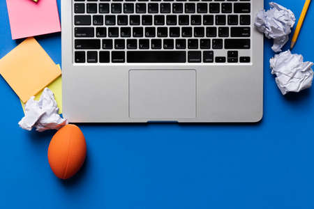 close up of computer, stress ball and crumpled paper with blue background, stress concept