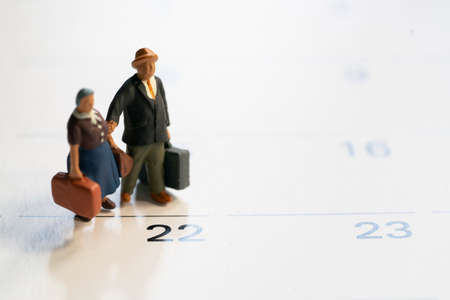 Miniature model family people, travelers standing on the calendar, traveling and planning concept