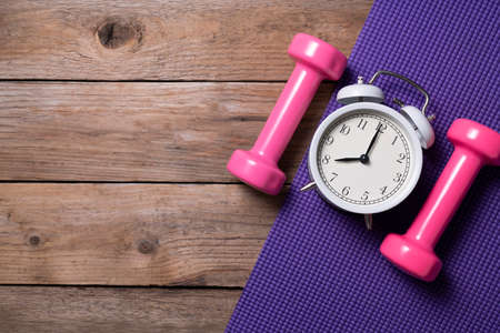Time for exercising alarm clock and dumbbell with colorful yoga mat backgroundの写真素材