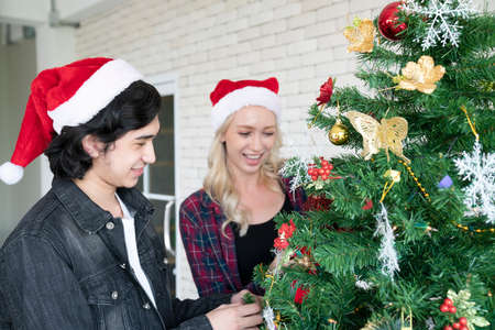 A couple or young people are gathering for Christmas and New Year party, smiling and decorate at each other, and celebrating the festivalの写真素材