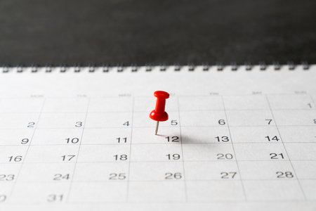 close up of red pin on calendar on black table background, planning for business meeting or travel planning conceptの写真素材