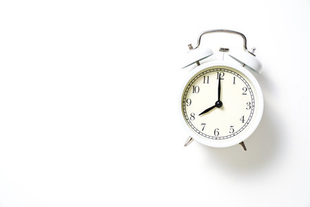 Retro alarm clock on white table background, vintage style flat lay