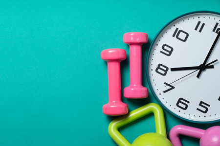 Time for exercising clock and dumbbell with green table backgroundの写真素材
