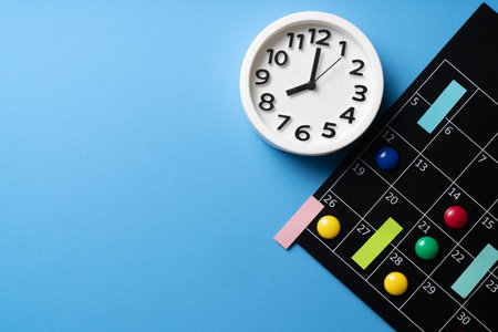 close up of calendar and alarm clock on the blue table background, planning for business meeting or travel planning conceptの写真素材