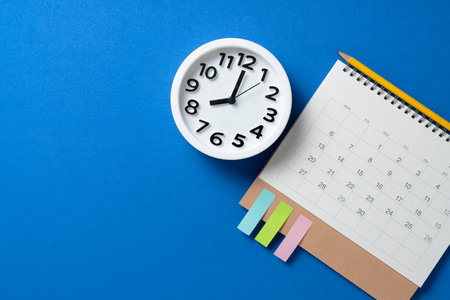close up of calendar and alarm clock on the blue table background, planning for business meeting or travel planning conceptの写真素材