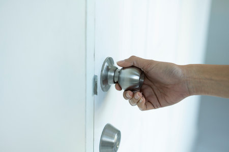 close up female hand holding a door knob or door handle in a houseの写真素材