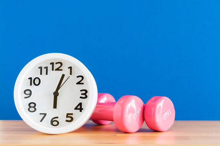 Time for exercising clock and dumbbell on the table with blue backgroundの写真素材