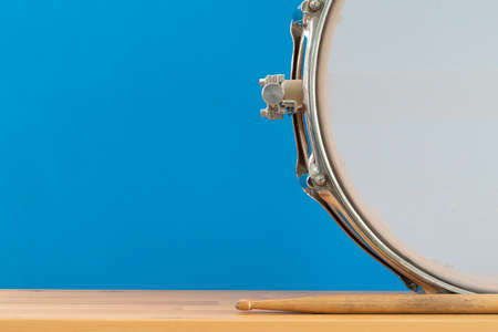 Close up drum stick and drum on table with blue background, front view, music conceptの写真素材