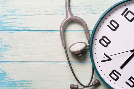Top view of stethoscope and clock on the wooden table background, schedule to check up healthy conceptの写真素材