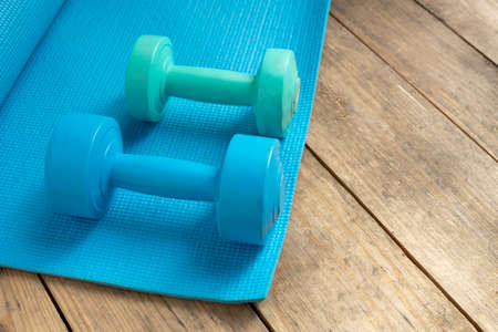 dumbbell and blue yoga mat on table, fitness healthy and sport conceptの写真素材