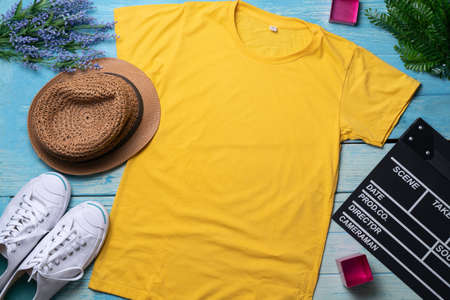 Mockup of a yellow t-shirt blank shirt template with accessories on the wooden blue table background, lifestyle and travel conceptの写真素材