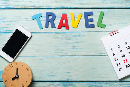 concept of travel vacation trip and long summer weekend planning with calendar, clock and mobile phone on blue wooden table backgroundの写真素材