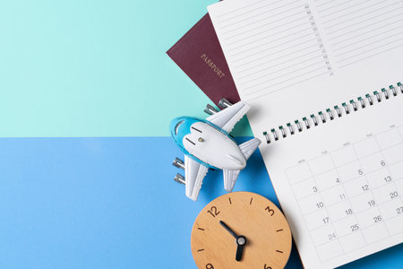 concept of travel vacation trip and long summer weekend planning, clock, calendar, passport on blue and green table backgroundの写真素材