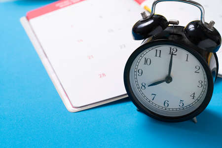 close up of calendar and alarm clock on the blue table background, planning for business meeting or...