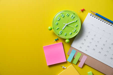 close up of calendar and alarm clock on the yellow table background, planning for business meeting or travel planning conceptの写真素材