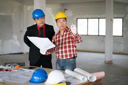 Asian engineers were consulted together and plan in construction site, engineering concept