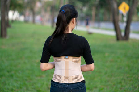 young asian woman wearing back support for protect her back, medicine and healthy conceptの写真素材