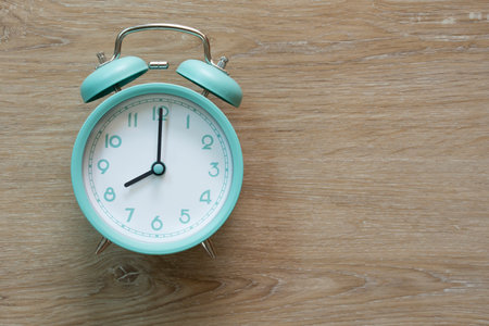 Retro green alarm clock on wooden table, vintage style