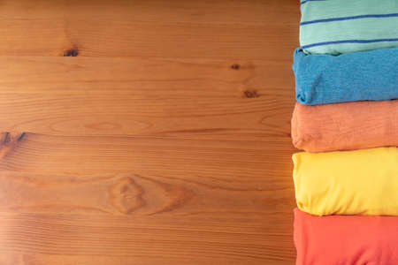 close up of rolled colorful t shirt clothes on wooden table background, travel conceptの写真素材