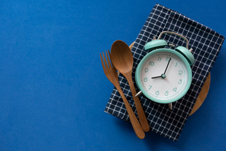 Food clock spoon and fork, Healthy food breakfast concept on blue table background