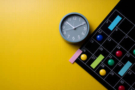 close up of calendar and alarm clock on the yellow table background, planning for business meeting...